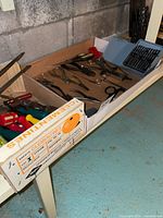 Overview of assorted tools in fruit box on shelf