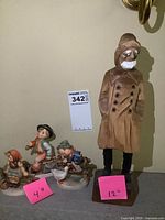Group shot showing three Hummel figurines with Old Salt wood carving and size labels 4 in and 12 in
