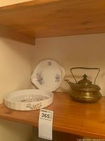 Overall view of quiche dish, cake plate and brass teapot on shelf