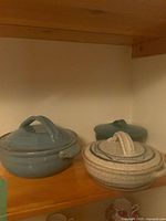 Three lidded pottery bowls on shelf