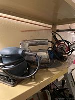 Group view of palm sander, sabre saw and heat gun blowers on shelf