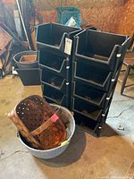 front view of stacked black resin bins with basket and pail in foreground