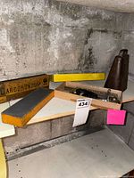 Shelf view showing Carborundum box and stone, flaring tool in tray, brass cow bell