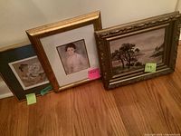 Three framed artworks leaning against wall showing full lot