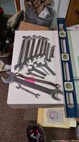 Group shot of sixteen wrenches and one blue spirit level on table