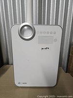 Front view of humidifier showing control dial, indicator panel, brand logo, and lot sticker