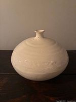 Front view of ivory globular vase showing geometric textures and small neck