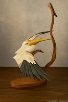 Full view of pelican carving on base against neutral backdrop