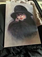 Full view of oil painting on canvas showing girl in black hat and coat