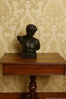 Full view of black classical bust on table