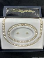Boxed set showing necklace, bracelet, earrings, and packaging text indicating freshwater pearls and 10KT