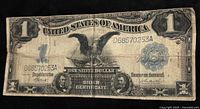 Front of the 1899 $1 silver certificate showing Black Eagle design, serial number, portraits and wear