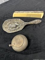 Brush, comb and tea light holder grouped on surface showing overall lot