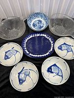 Full group showing all eight items: four koi bowls, two clear glass bowls, blue platter, blue-white bowl