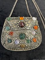 Front view of metal purse showing filigree detail and inset stones