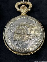 Closed pocket watch showing embossed locomotive design