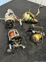 All four fishing reels arranged on black surface