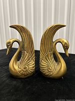 Front view of both brass swan bookends showing mirrored design