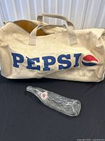Canvas Pepsi duffel bag and flattened bottle side by side