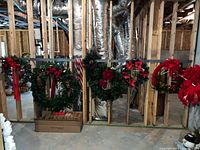 Five wreaths hung on wall studs showing size differences and decorations