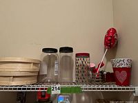 Shelf with wooden baskets, two clear plastic canisters, patterned tumbler, flower pots, balloon