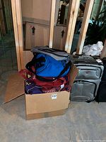 Box containing assorted tote bags stacked, blue tote visible on top