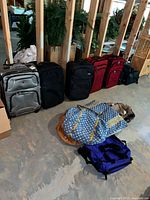 Line of six wheeled suitcases plus five soft bags on floor