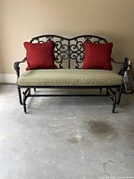 Full view of black metal glider bench with cushion and pillows