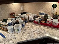 Countertop view of entire lot showing all mugs, pitchers, French press, travel mug and trays