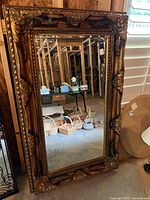 Full view of ornate mirror leaning against wall