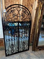Full view of black wrought iron mirror showing scrollwork and arched top