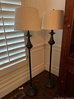 Two metal floor lamps with shades side by side