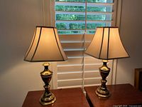 Both brass table lamps lit, front view