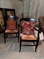 Pair of dark wood armchairs with rush seats and pillows