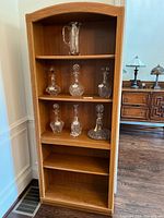 Front view of medium-tone particle board bookshelf with glassware shown for scale