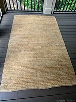Full view of rectangular natural jute rug laid flat, shows overall color and size