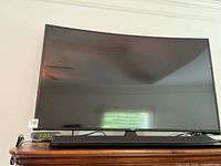 Front view of Samsung curved TV with Sony soundbar on dresser
