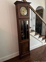 Full view of oak grandfather clock beside staircase