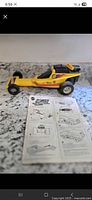Full side view of yellow Mattel Power Shifters dragster with instruction manual visible below it on a countertop.