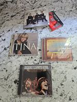 Four CD jewel cases and one audio cassette tape on a granite countertop. The Rankin Family CD is on top signed in black marker.