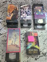 Five assorted VHS tapes laid out including Braveheart, Gandhi, The Secret of NIMH, Lawrence of Arabia, and Star Trek: First Contact.