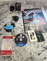 Overview of all items in the lot including the games, bulbs, mini lights, cassette tapes, and Superman poster book.