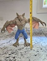 Man-Bat figure next to a measuring tape showing approximately 11 inches in height.