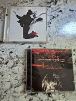 Top view of Bryan Adams Anthology and The Best of Me CD cases on a speckled countertop.