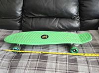 Side view of green Penny skateboard on fabric surface showing deck, wheels and trucks