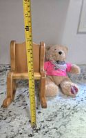 Wooden rocking chair with measuring tape showing height near 16 inches and stuffed bear in background.