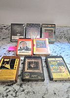 Photo showing all 8 tapes arranged in two rows on granite surface. Four tapes sealed in original plastic wrap at back, four opened tapes in front.