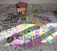 Assorted Pokemon cards spread out with Charizard metal tin visible