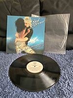 Photo of album cover, vinyl record and protective plastic sleeve showing condition and included items