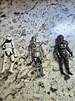 Three Star Wars figures: Stormtrooper, 2-1B Droid, and Death Star Gunner on a stone counter